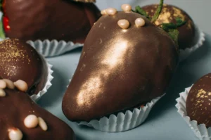 Close-up view of strawberry covered with chocolate decorated with edible gold