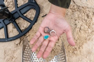 A hand displaying assorted gold jewelry found using a metal detector
