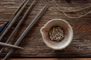 Melting pot with silver metal granules on wooden table with jeweler tools, jewelry making workshop