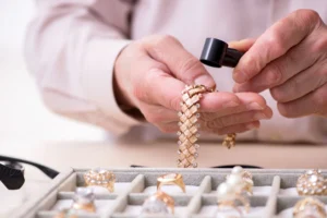 A jeweler examines a gold bracelet with a jeweler's loupe