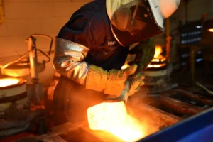 A melter pouring molten precious metals; precious metals refining