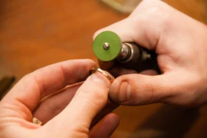 Hand of a jeweler using a polishing tool to finish a gold ring